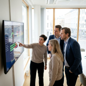 Ledere og IT-medarbejdere gennemgår et dashboard i et kontor, mens de diskuterer kontrol med AI-agenter.