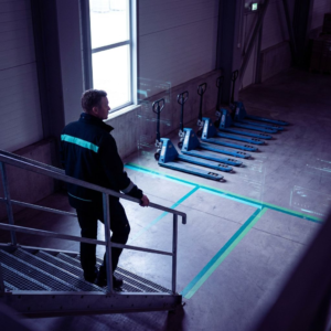 Beslutningsøjeblik i et nordisk operationsrum: en leder ser en kø af opgaver holdes tilbage ved et enkelt kontrolpunkt. Dyb purpur/indigo stemning med cyan/grønne signalaccents.