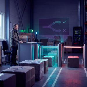 Nordisk dispatch‑scene: en operationsleder ved en kø af pakker og en lav fysisk gate, køligt lys med indigo skygger og cyan accenter; et øjeblik af beslutning mellem at lade flowet fortsætte eller stoppe det.