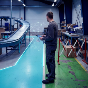 Nordisk SMV‑leder i en plukzone tøver mellem to farvekodede gulvbaner (cyan vs grøn) der symboliserer to pipeline-ruter; indigo skygger og subtile data-pulser i luften.