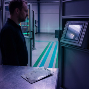 Nordisk operationsscene i en lille produktionshal: en teknisk leder vurderer et testsite med cyan/indigo lys og svag data‑pulse, symboliserer beslutningen om multimodal drift og tradeoffs mellem omkostning og latency.