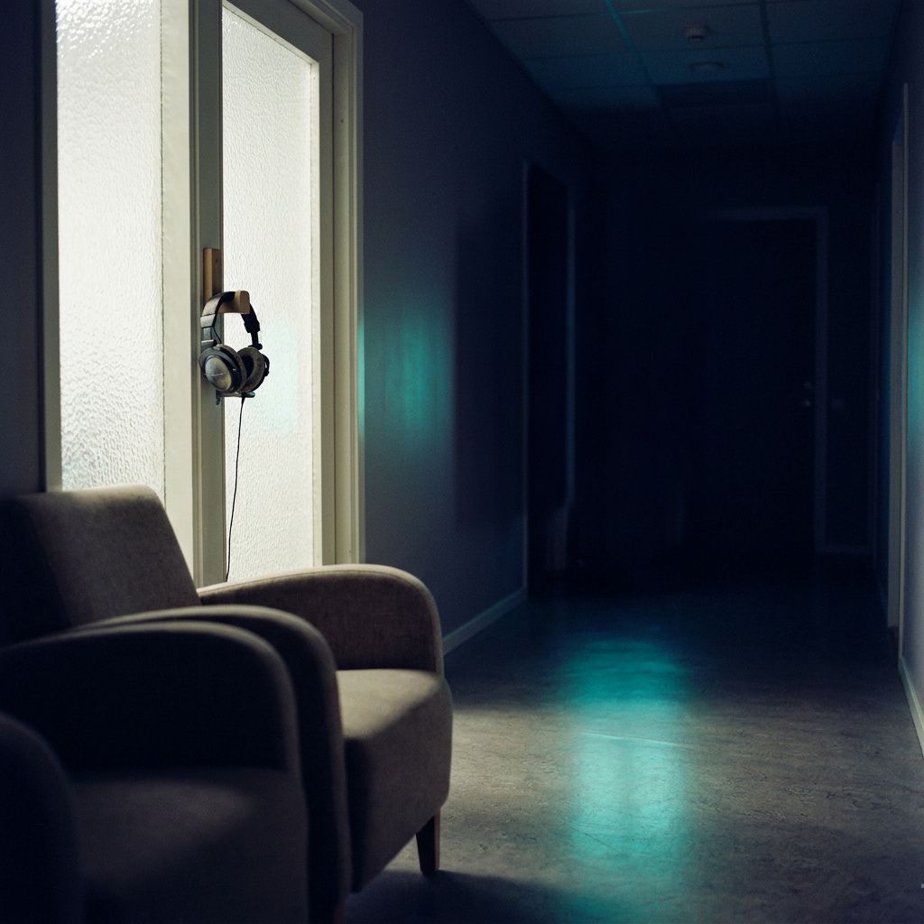 Diskret detalje fra kriseservice med headset på krog ved lukket dør og tomme stole i baggrunden